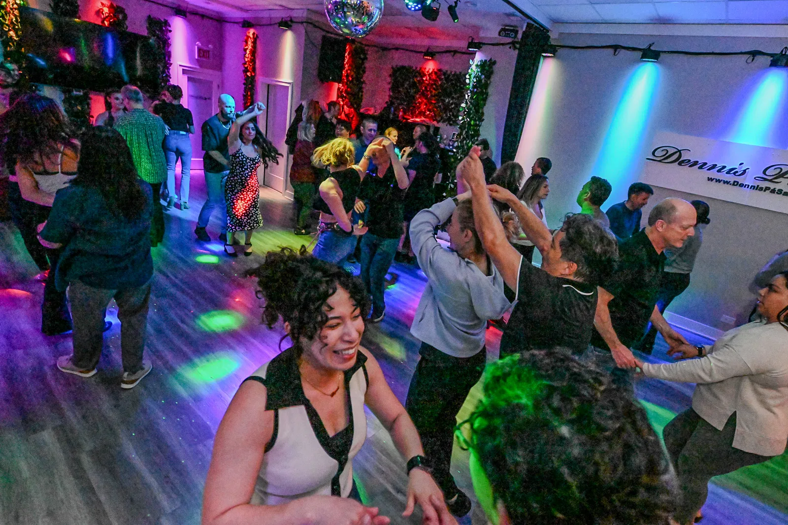 Students smiling while dancing at a Dennis PaSamba social night