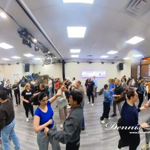 Diverse group of adults smiling and dancing in a lively beginner Latin dance class, high energy fun atmosphere